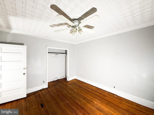 unfurnished bedroom featuring a closet, baseboards, a ceiling fan, crown molding, and hardwood / wood-style flooring