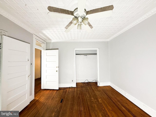 unfurnished bedroom featuring an ornate ceiling, wood-type flooring, baseboards, and a closet