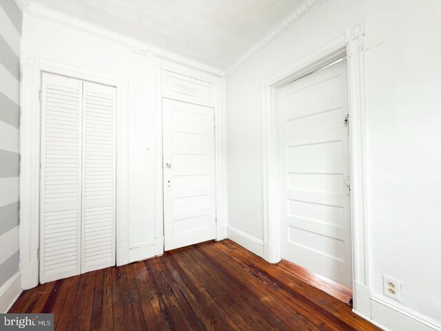 unfurnished bedroom with a closet, baseboards, and dark wood finished floors