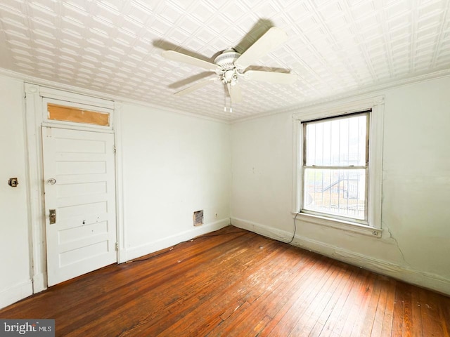 empty room featuring visible vents, baseboards, ceiling fan, hardwood / wood-style flooring, and crown molding