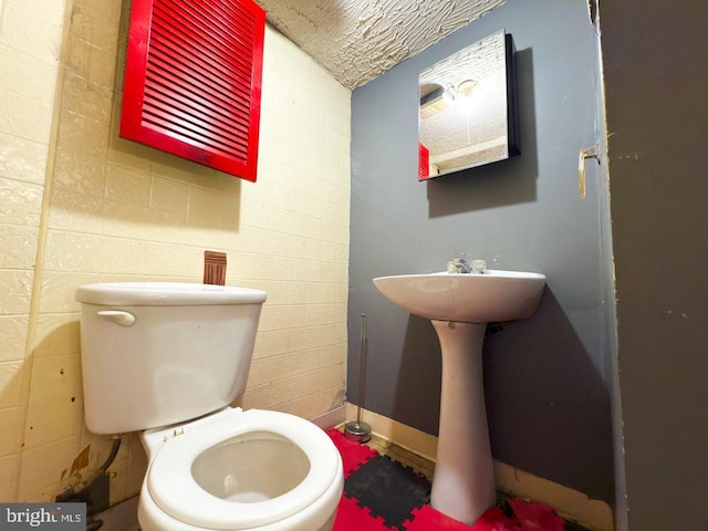 bathroom with toilet and concrete block wall