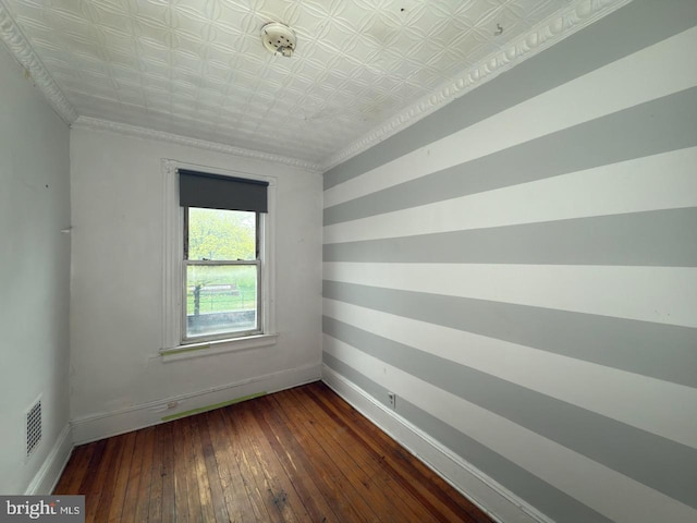 empty room with hardwood / wood-style floors, visible vents, baseboards, and an ornate ceiling
