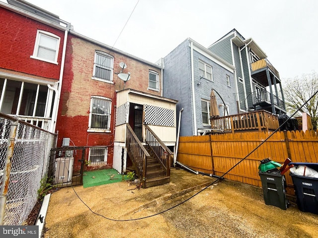 back of property featuring entry steps, fence, and brick siding