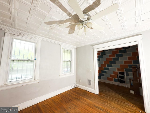 unfurnished room with visible vents, baseboards, dark wood finished floors, and an ornate ceiling