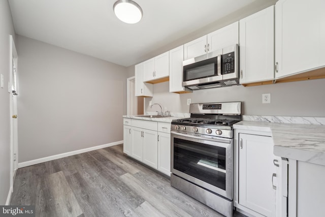 2325 W 4th St, Chester, PA 19013 - kitchen featuring baseboards, white cabinetry, a sink, light wood-style flooring, and stainless steel appliances
