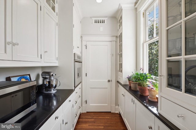 3712 Bradley Ln, Chevy Chase, MD 20815 - kitchen with stainless steel microwave, dark countertops, white cabinets, dark wood-type flooring, and oven