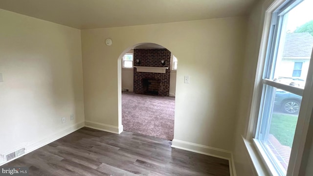 710 Roger St, Salisbury, MD 21804 - unfurnished room featuring a brick fireplace, dark wood-style flooring, and arched walkways