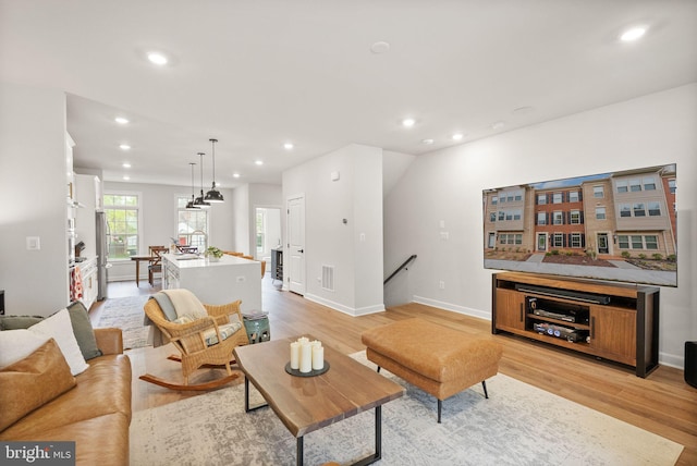 living area featuring light wood-type flooring, recessed lighting, and baseboards