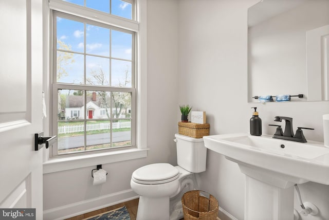 half bathroom featuring baseboards, toilet, and wood finished floors