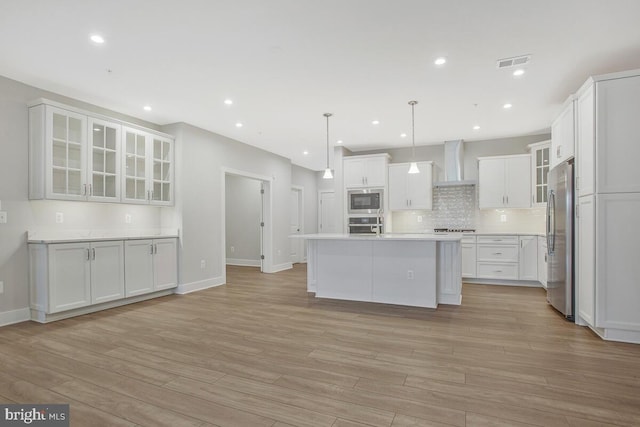 170 Harrier Way Unit 11, Chester, MD 21619 - kitchen featuring visible vents, wall chimney exhaust hood, light wood-style floors, and stainless steel appliances