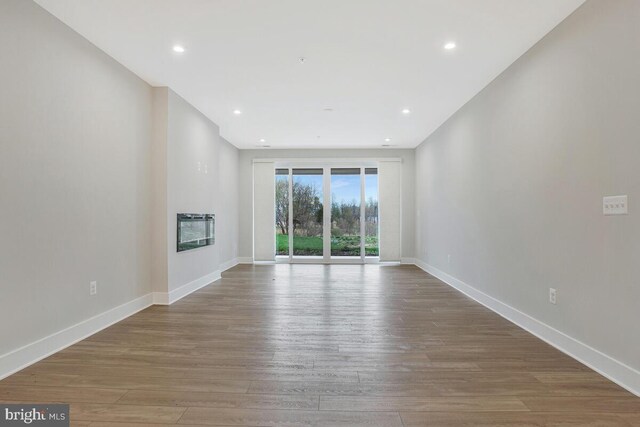 170 Harrier Way Unit 11, Chester, MD 21619 - unfurnished living room featuring a glass covered fireplace, recessed lighting, baseboards, and wood finished floors