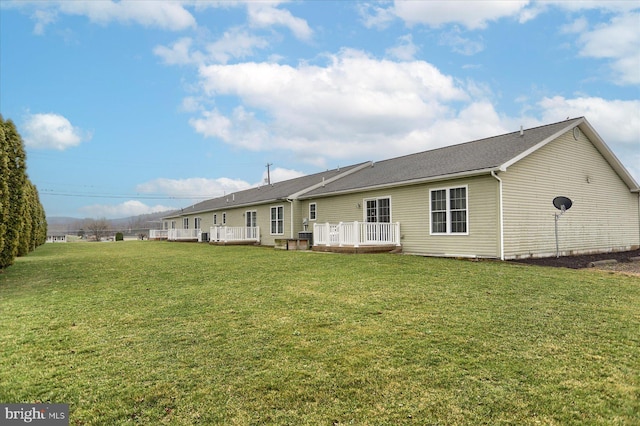 back of property with a yard and a wooden deck