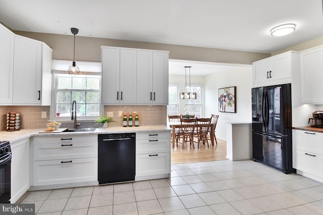 kitchen with white cabinets, black appliances, light tile patterned flooring, a sink, and backsplash