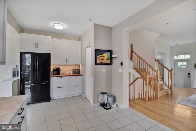 kitchen with white cabinets, light tile patterned floors, freestanding refrigerator, and decorative backsplash