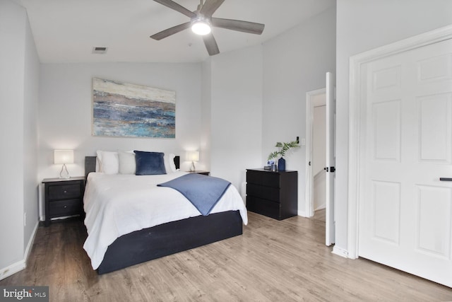 bedroom with visible vents, baseboards, a ceiling fan, wood finished floors, and vaulted ceiling