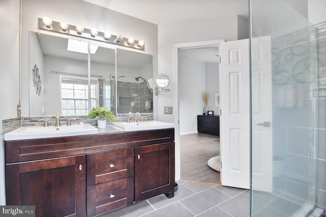 bathroom featuring a stall shower, double vanity, a sink, and tile patterned floors