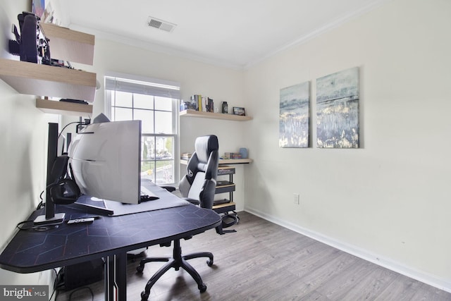 office space featuring crown molding, visible vents, baseboards, and wood finished floors