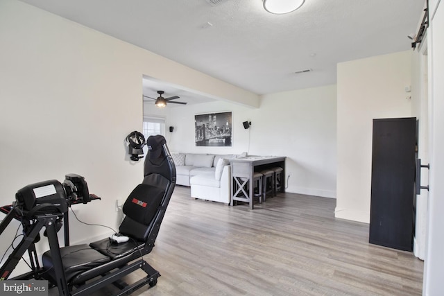 workout room featuring ceiling fan, wood finished floors, and baseboards