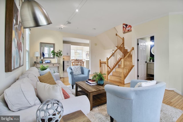 living area with track lighting, light wood-type flooring, stairway, and baseboards