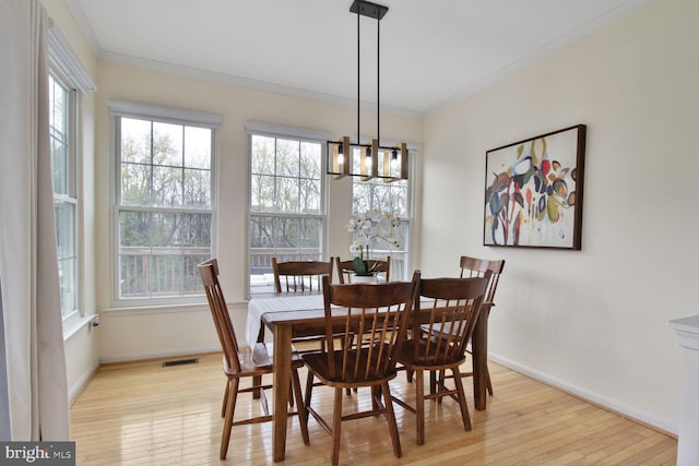 dining area featuring a notable chandelier, baseboards, light wood-style flooring, crown molding, and visible vents