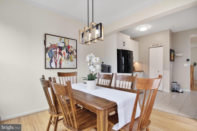 dining area featuring light wood-style floors, baseboards, and an inviting chandelier