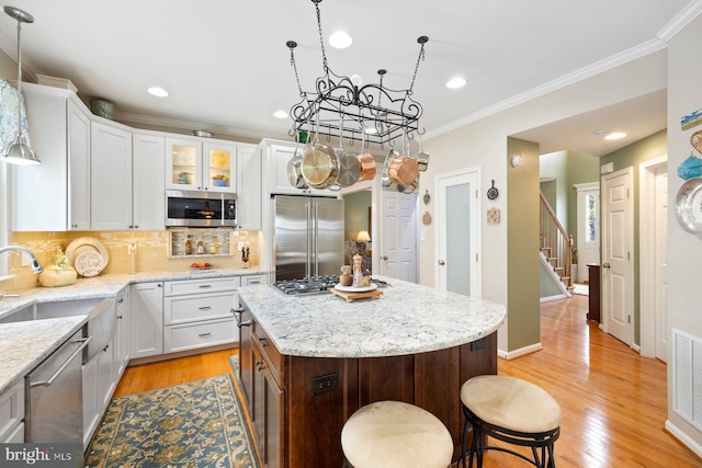 kitchen featuring stainless steel appliances, a sink, tasteful backsplash, a kitchen bar, and a chandelier