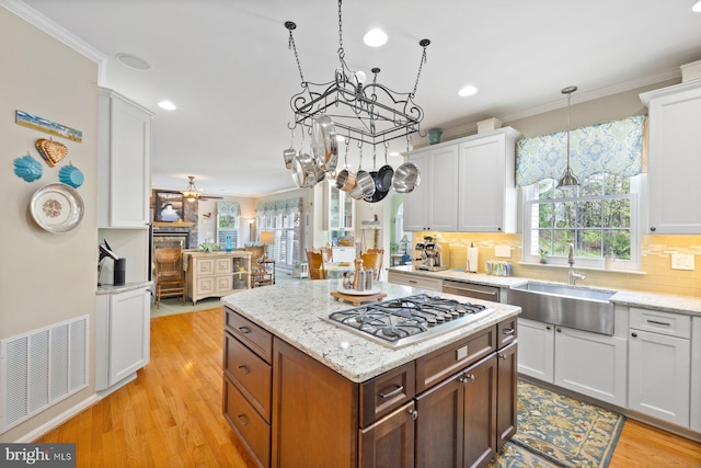 kitchen featuring visible vents, white cabinetry, ornamental molding, and a sink