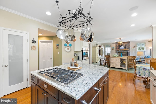 kitchen with light stone counters, stainless steel appliances, an inviting chandelier, light wood-type flooring, and crown molding