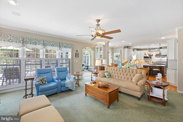 living room featuring light colored carpet, a ceiling fan, and a healthy amount of sunlight