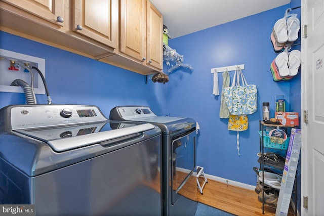 laundry room with cabinet space, wood finished floors, washing machine and clothes dryer, and baseboards