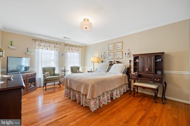 bedroom featuring light wood-type flooring, visible vents, crown molding, and baseboards
