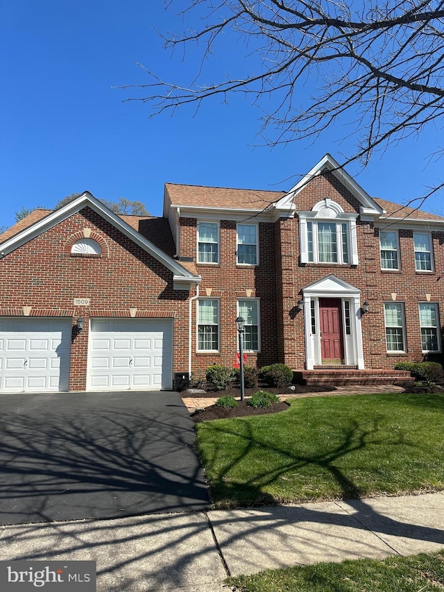 colonial house with brick siding, a front lawn, a garage, and aphalt driveway