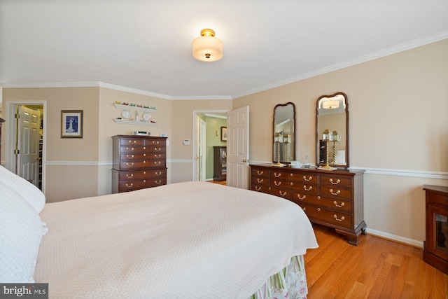 bedroom featuring light wood-style floors, baseboards, and ornamental molding