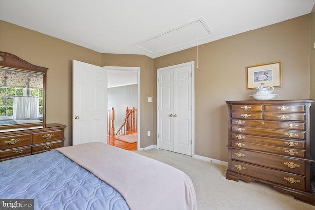 bedroom with attic access, light carpet, and baseboards
