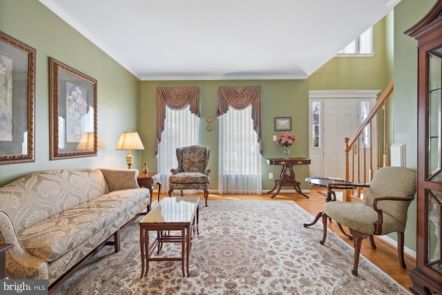 living area featuring wood finished floors, baseboards, and ornamental molding