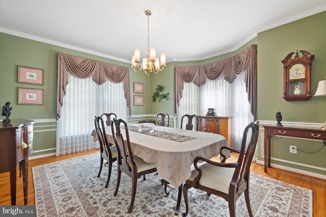 dining area with wood finished floors, a notable chandelier, and crown molding