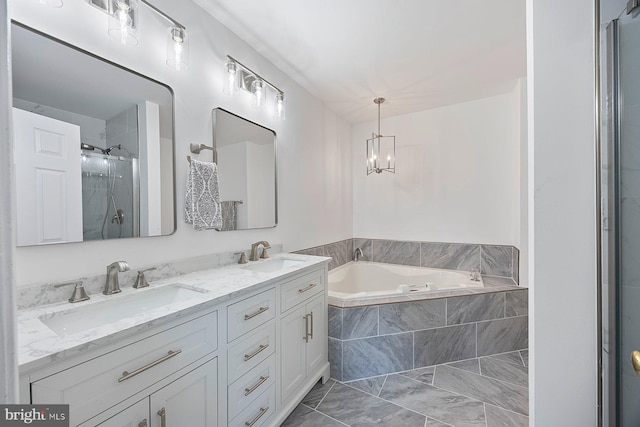 bathroom with an inviting chandelier, a garden tub, a stall shower, and a sink