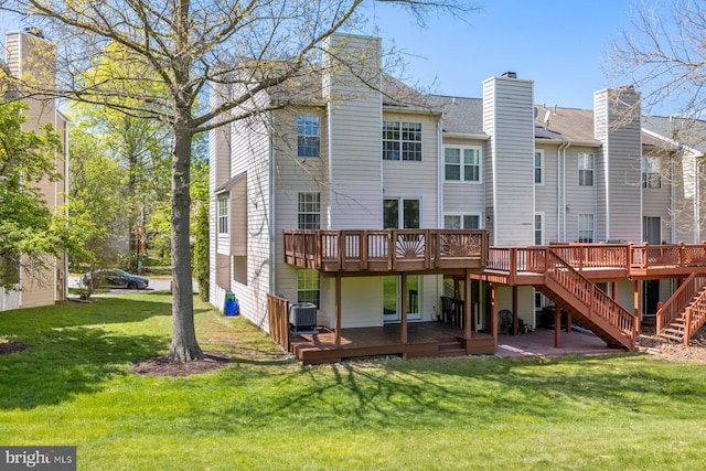 rear view of house featuring stairway, a chimney, cooling unit, a wooden deck, and a lawn