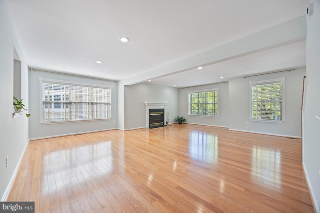 unfurnished living room with a fireplace with flush hearth, light wood finished floors, baseboards, and recessed lighting
