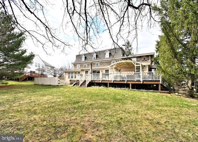 rear view of property with a wooden deck, a lawn, and stairs