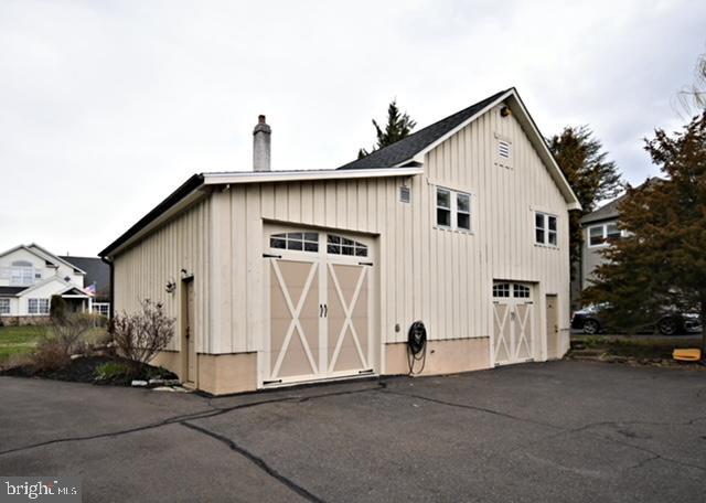 exterior space featuring board and batten siding, a detached garage, and a chimney