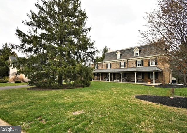 rear view of property featuring a porch and a yard