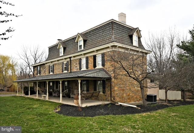 back of house with a porch, a chimney, a yard, and cooling unit