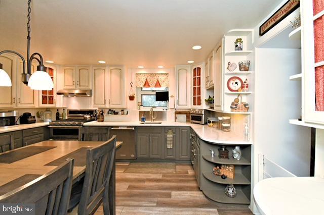 kitchen with stainless steel range with gas stovetop, gray cabinets, open shelves, dishwasher, and under cabinet range hood