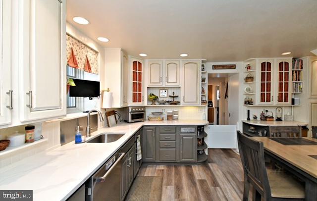 kitchen featuring open shelves, dishwasher, wood finished floors, gray cabinets, and a sink