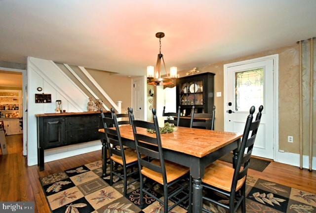 dining room featuring stairway, an inviting chandelier, and wood finished floors