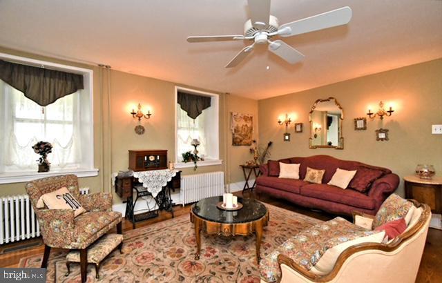 living room featuring ceiling fan, radiator heating unit, and wood finished floors