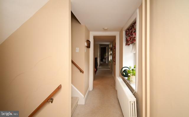 corridor with light carpet and radiator