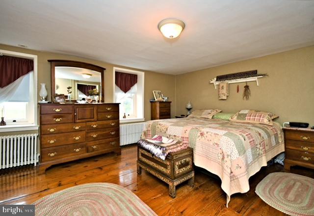 bedroom with hardwood / wood-style flooring and radiator heating unit