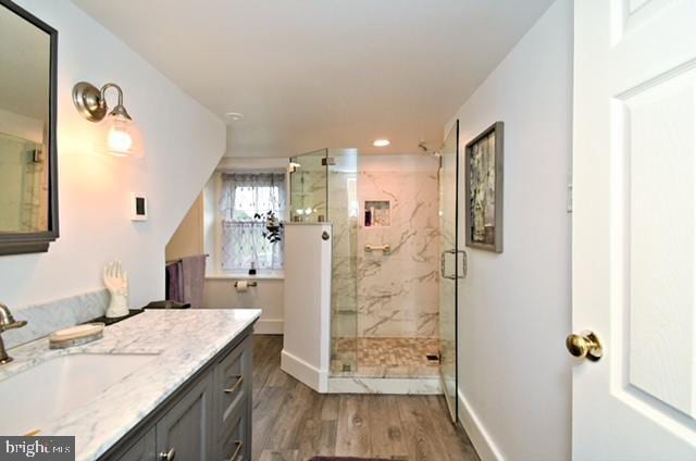 bathroom featuring a marble finish shower, baseboards, recessed lighting, wood finished floors, and vanity